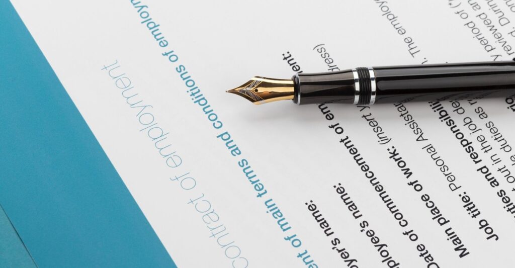 a black fountain pen with a gold tip lying down on a piece of paper titled 'contract of employment'.