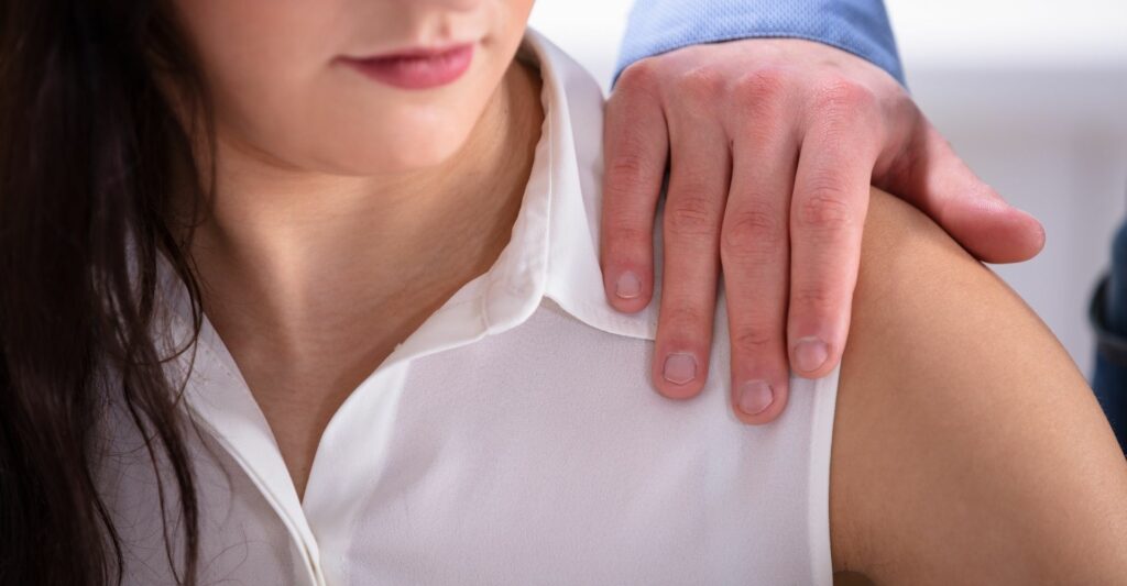 A close up of a woman's shoulder with a man's hand sitting on top of it.