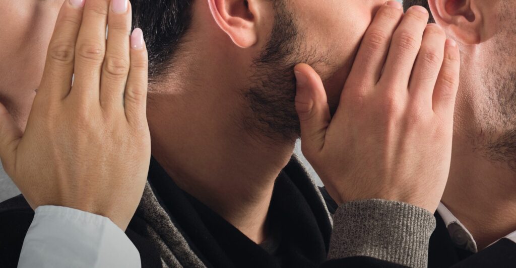 A close up image of 3 side profile faces. The left woman is covering her hand and whispering something to the man in the middle, and the man in the middle is whispering something to the man on the right,