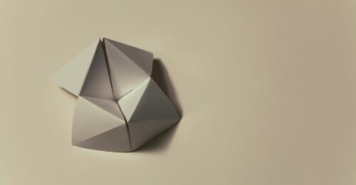 An image of a blank cream coloured origami moving flexagon sitting on top of a cream coloured background.