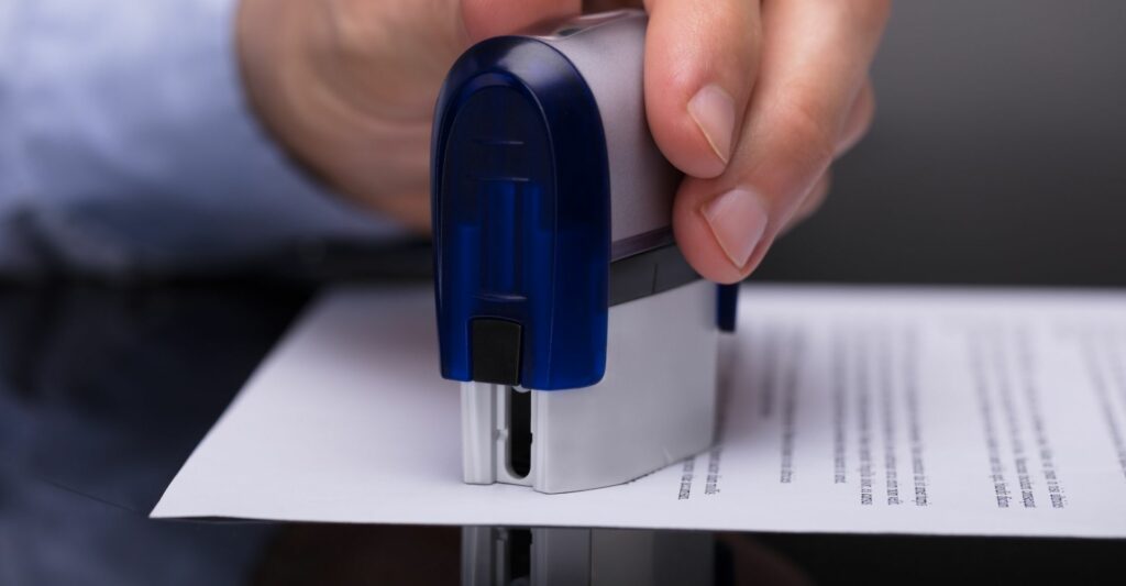 A close up image of someone stamping a document with a large metal stamp.