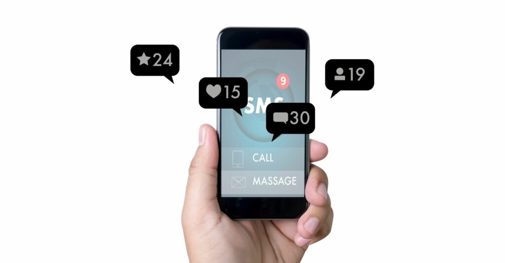 An image of a person holding up a black phone in their left hand with four speech bubble graphics coming out of the screen which are social media notifications for likes, starred, contacts and messages.