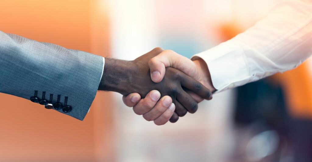 A side close up photo of 2 men shaking hands.