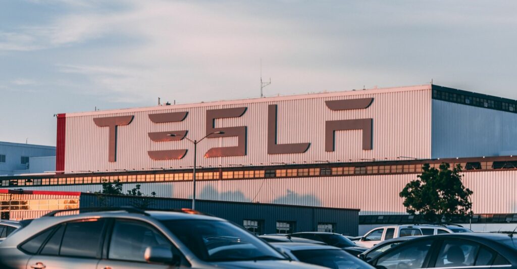 A photo of a tesla warehouse from the front, showing clearly, the Tesla company name.