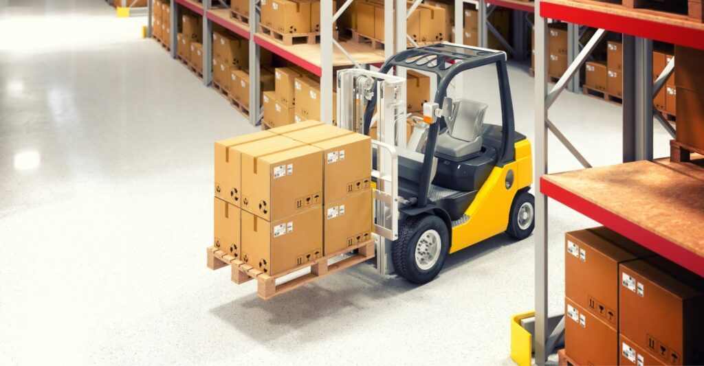 A photo of a small yellow forklift in a warehouse carrying 8 cardboard boxes.