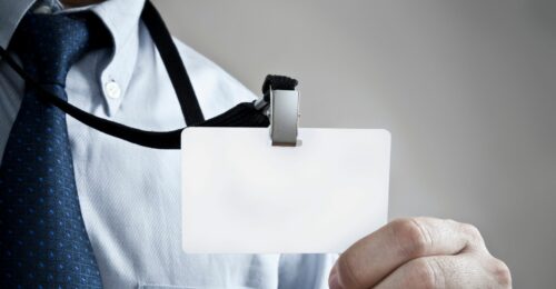 A photo of an employee holding out their employee card on a lanyard.