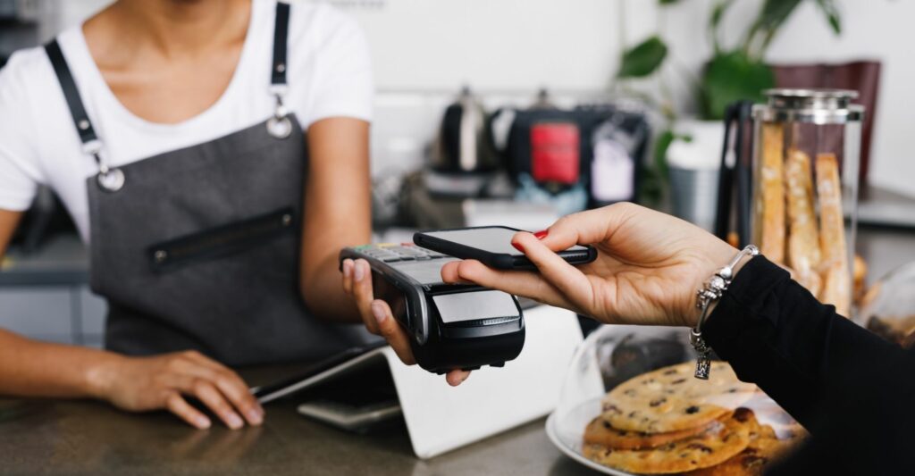 An image of a customer tapping their phone onto an eftpos machine to pay at a cafe.