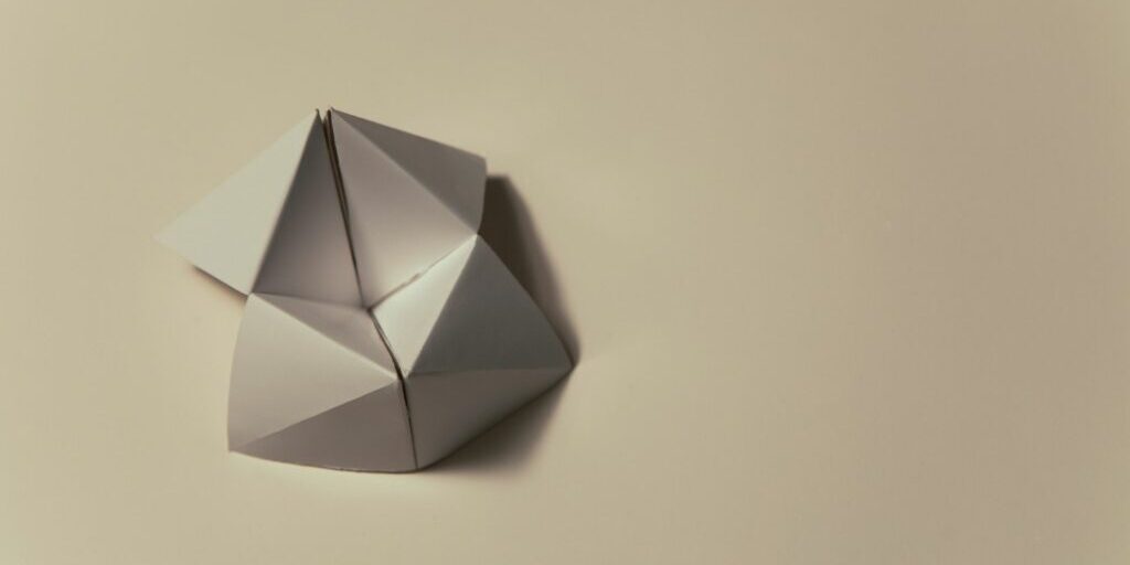 An image of a blank cream coloured origami moving flexagon sitting on top of a cream coloured background.