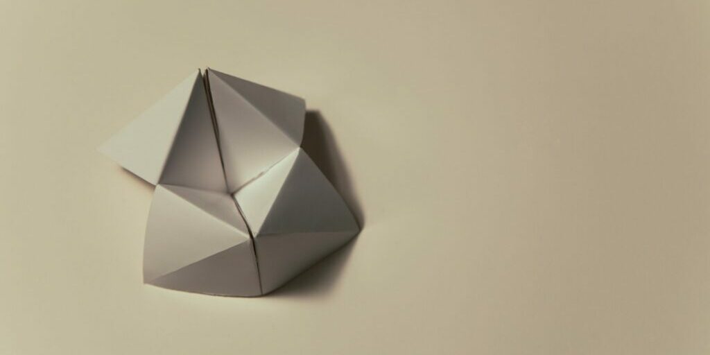 An image of a blank cream coloured origami moving flexagon sitting on top of a cream coloured background.