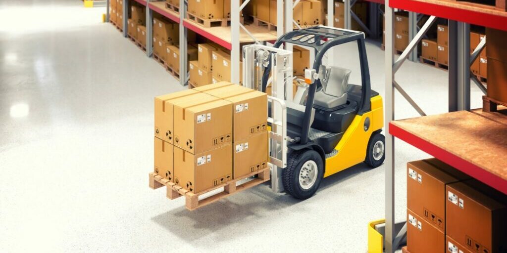A photo of a small yellow forklift in a warehouse carrying 8 cardboard boxes.