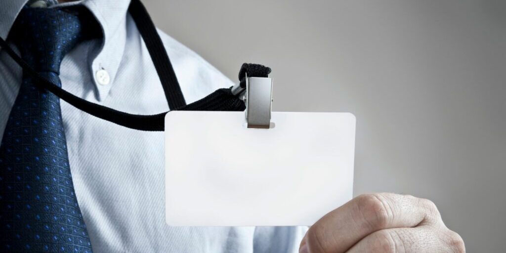 A photo of an employee holding out their employee card on a lanyard.