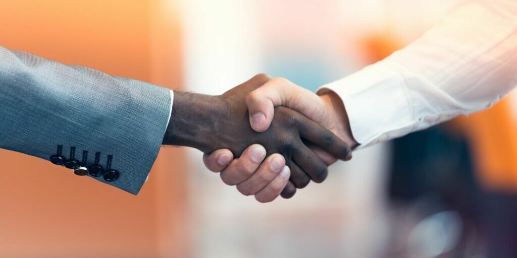 A side close up photo of 2 men shaking hands.