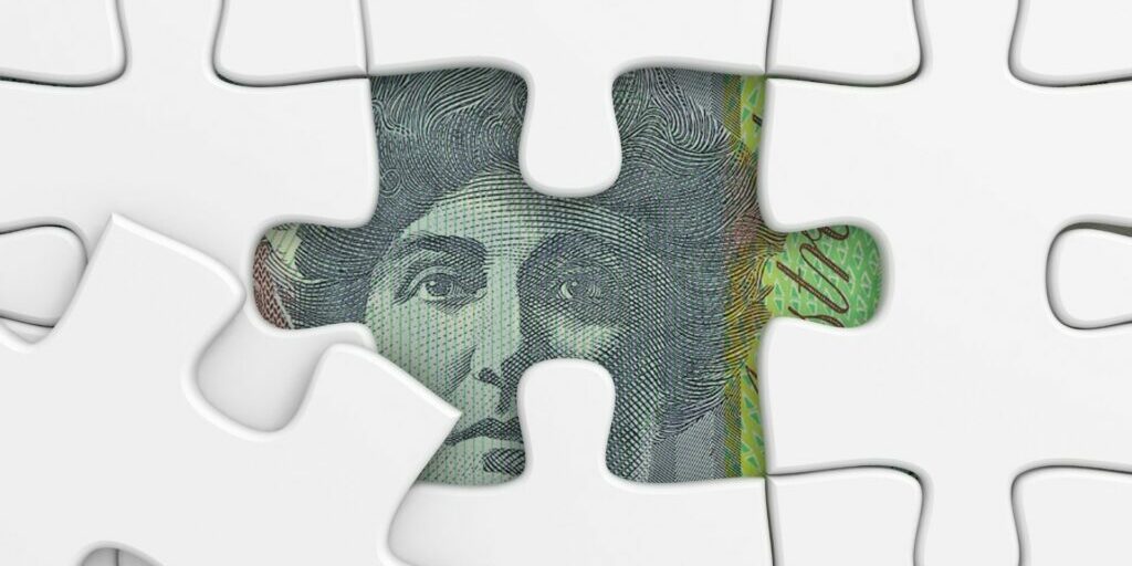 An image of a pure white puzzle with one piece removed to reveal a part of the Australian $100 note,