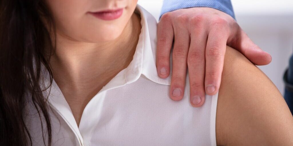 A close up of a woman's shoulder with a man's hand sitting on top of it.