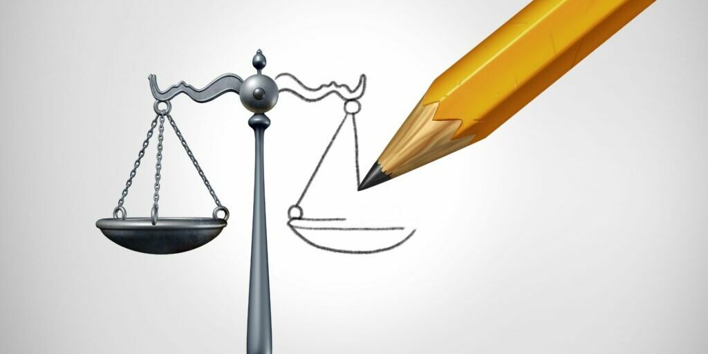 A graphic illustration of a pencil finishing off a drawing of the justice scales